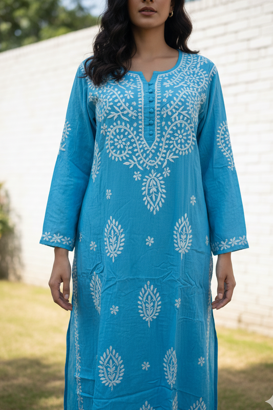 Woman wearing a blue embroidered dress standing outdoors.
